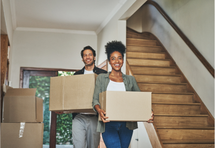 Couple carrying packed boxes out of a house